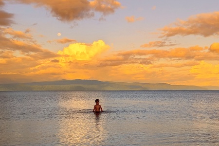 Jeune enfant se baigne au coucher du soleil dans le golfo dulce