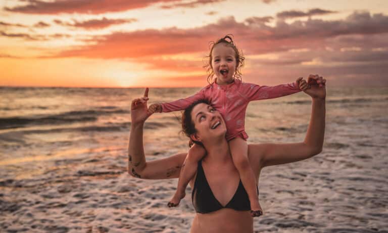 une mère, son enfant et sa fille s'amusent au coucher du soleil.